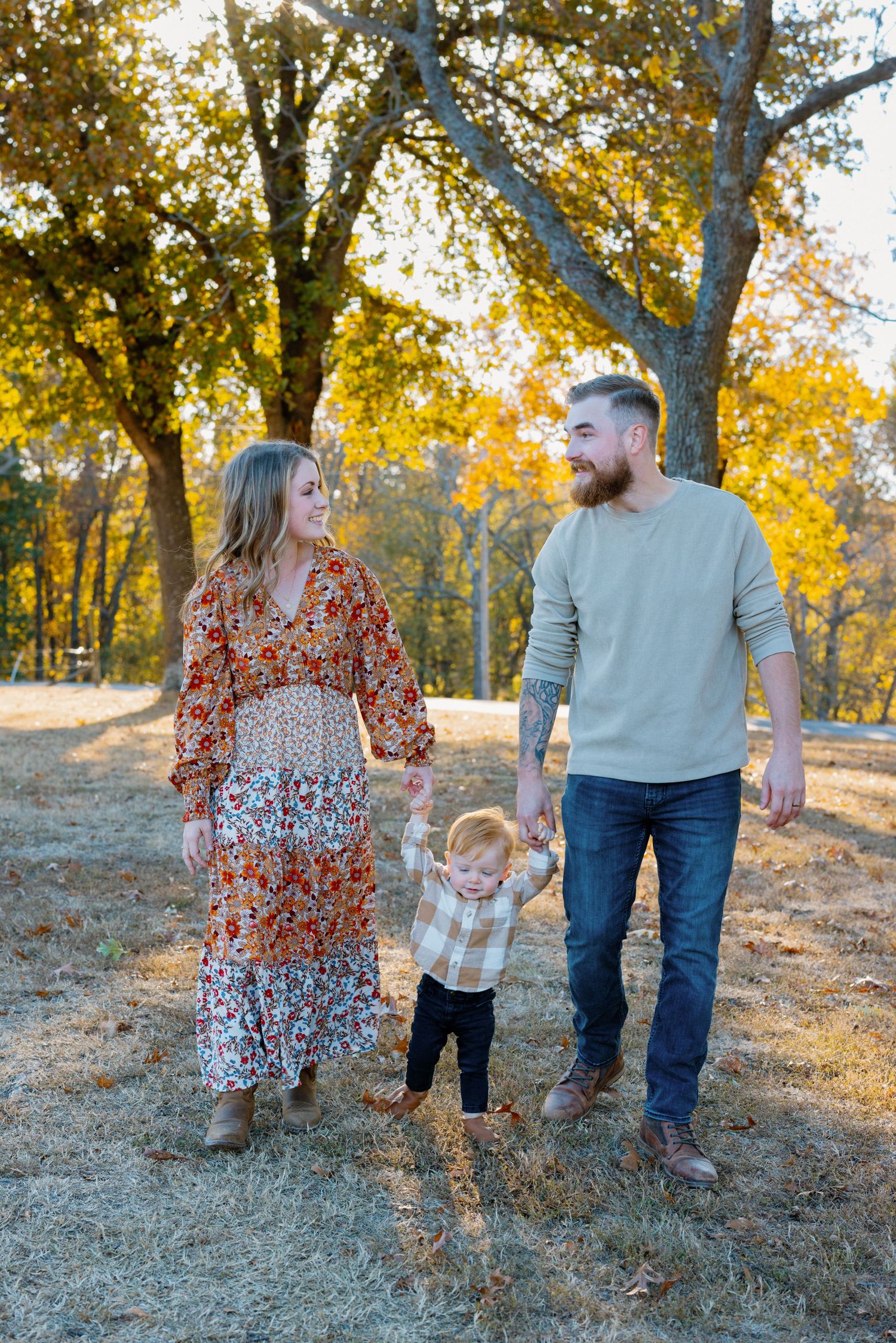 Family walking together on autumn trail while holding hands with small child.