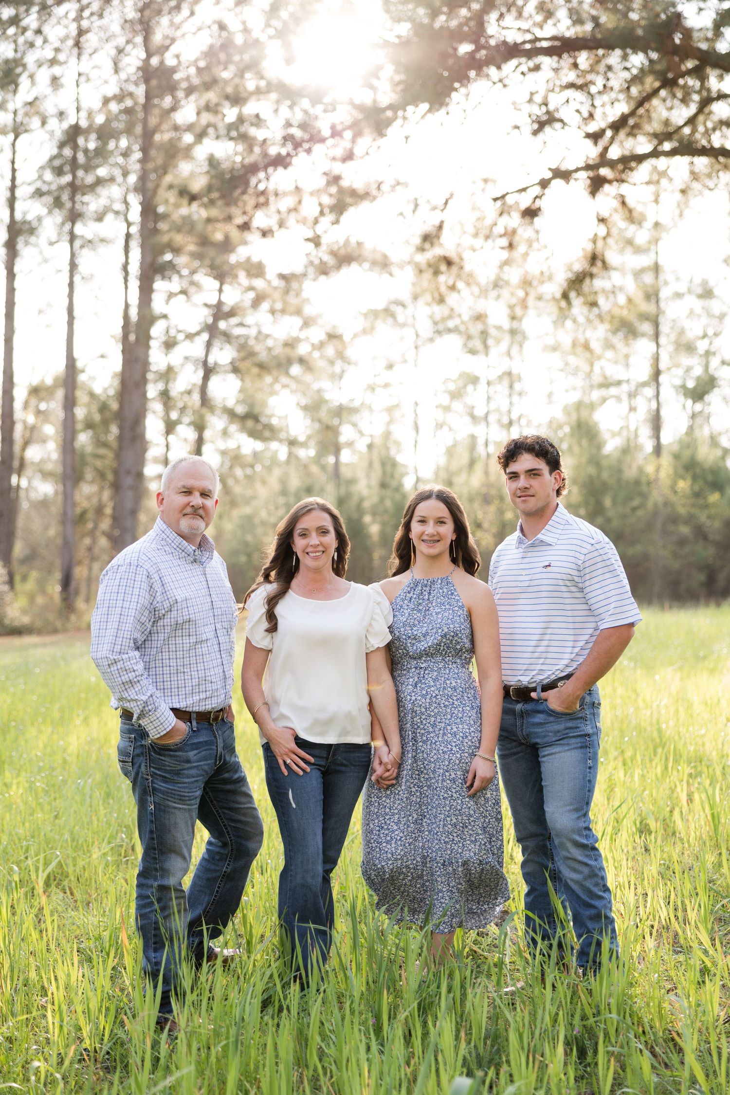 A happy group walks together through a sunlit meadow of tall grass during golden hour.
