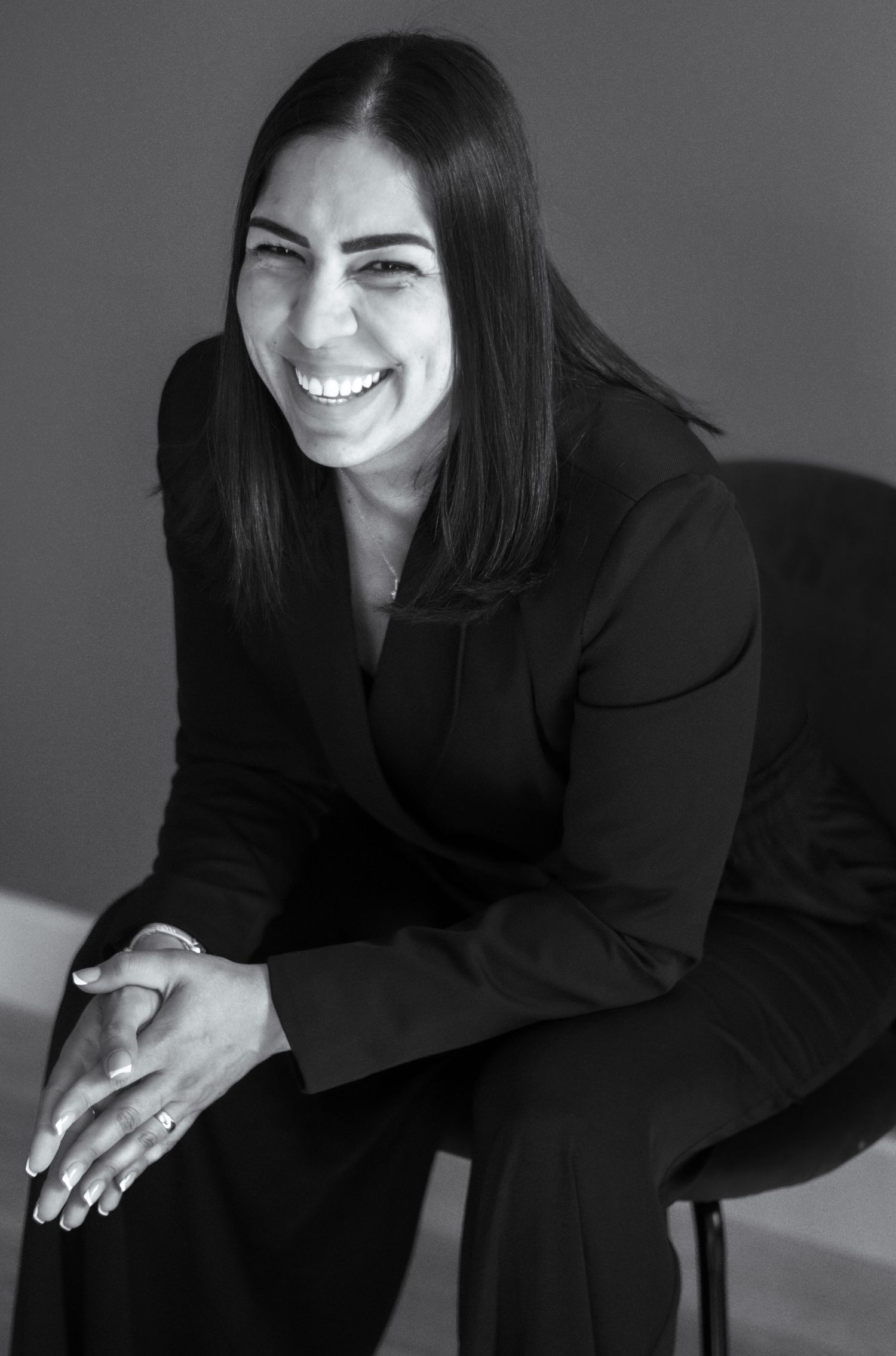 A professional woman in a dark blazer smiles warmly in a black and white portrait photograph.