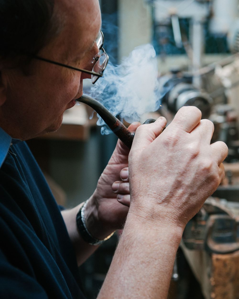 Close-up shots of someone smoking a pipe, showing the ritual of lighting and enjoying tobacco.