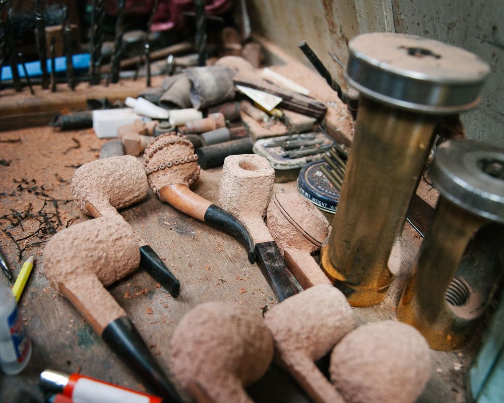 Clay pipes and tobacco accessories arranged on a rustic wooden surface.