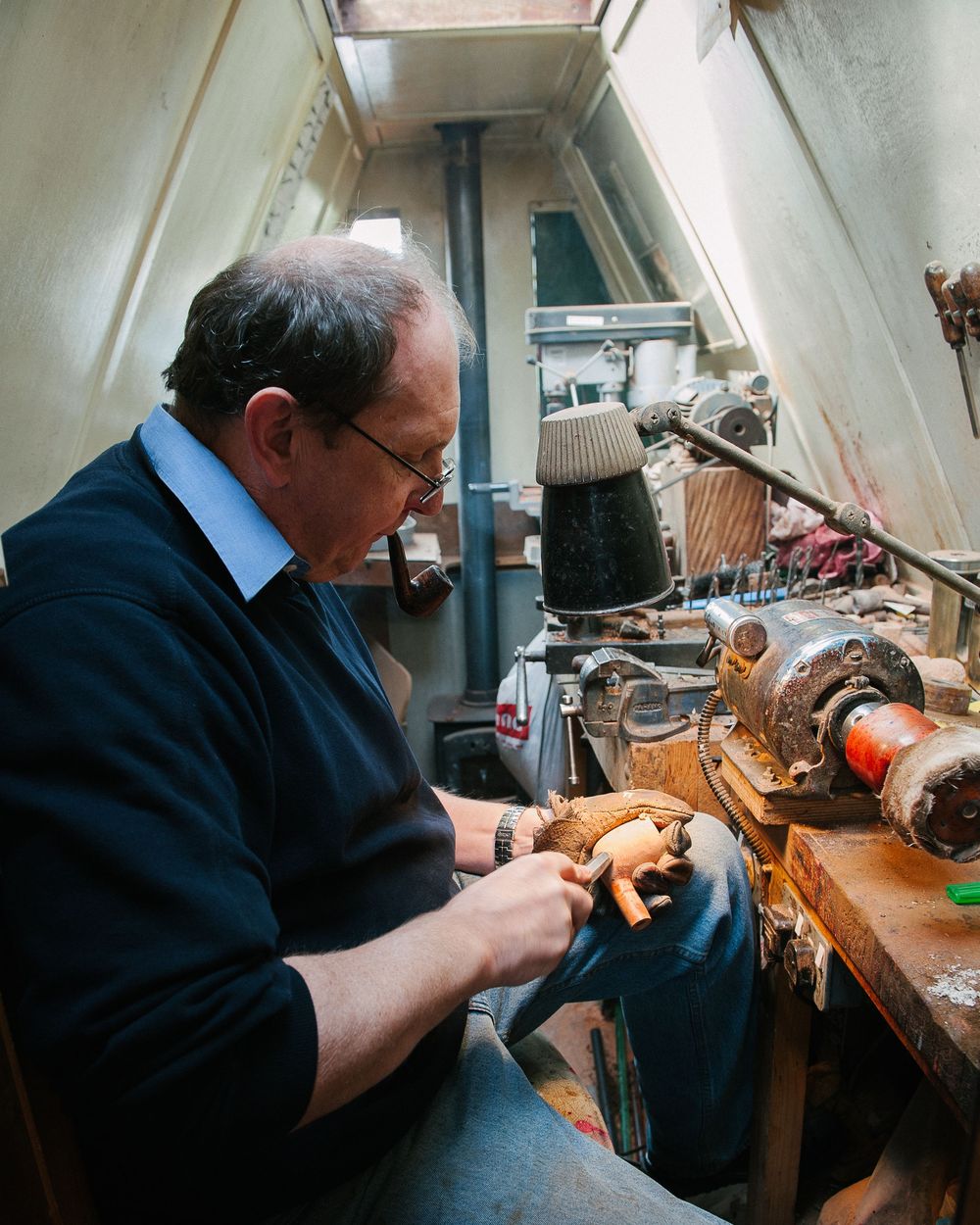 Craftsperson working at a traditional workbench in a dimly lit workshop.