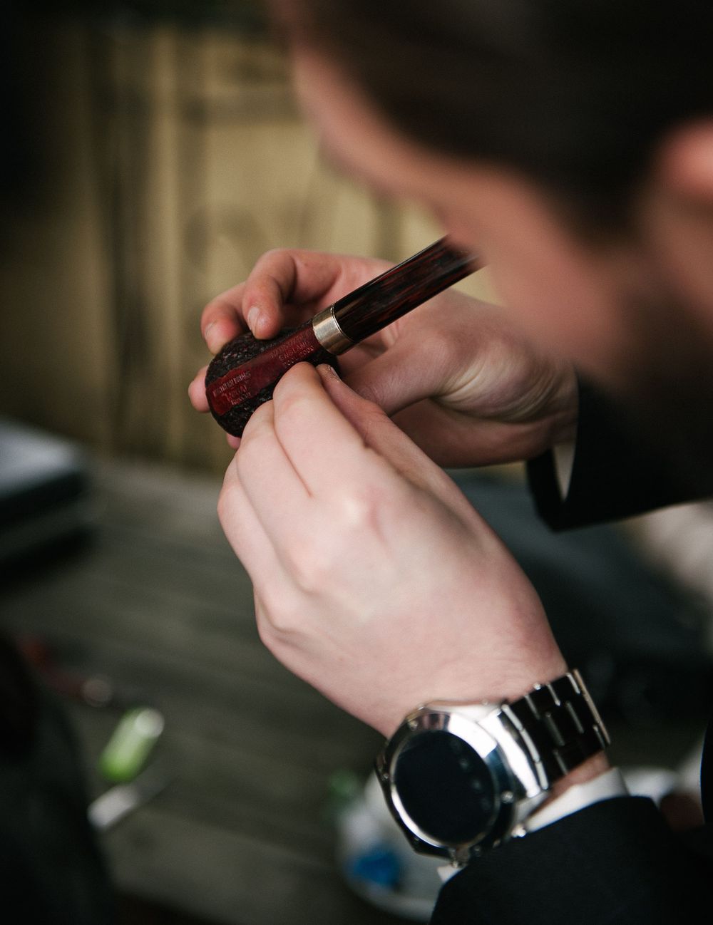 Close-up sequence of hands holding and preparing a smoking pipe.
