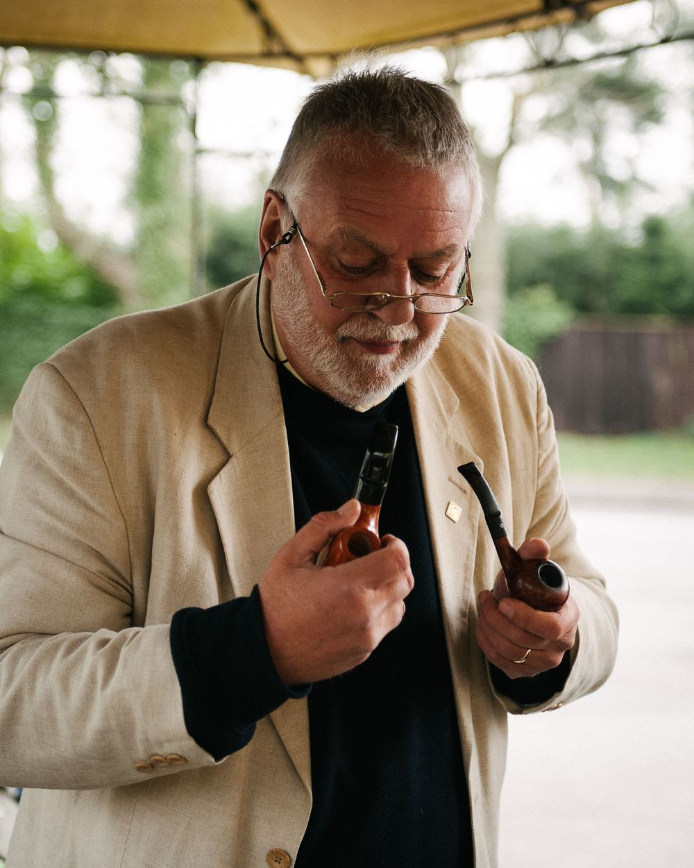Person in cream jacket demonstrating proper pipe smoking technique.