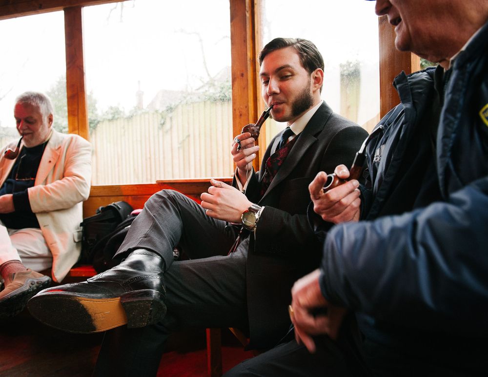 Group of people examining and discussing pipes in a wood-paneled room.