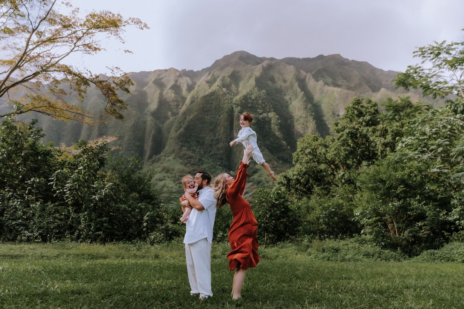 People dancing and celebrating together on a grassy field with mountains in the background.