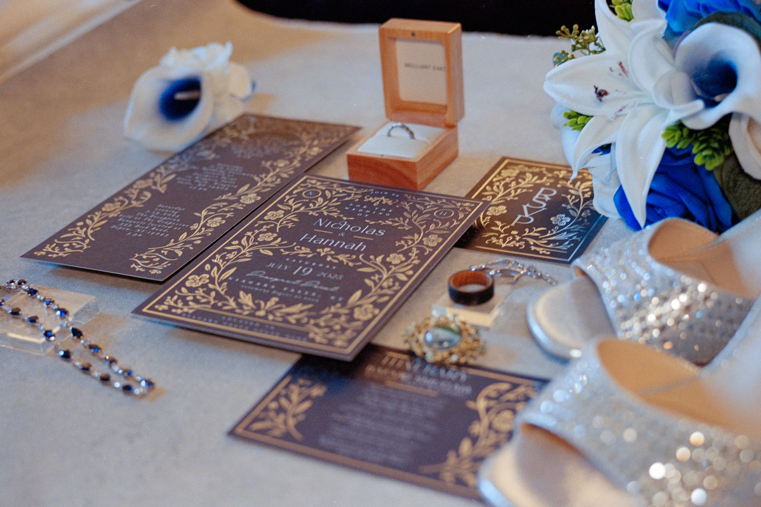 Decorative wedding table setup with engraved wooden menu cards, blue and white floral arrangements, and elegant place settings.
