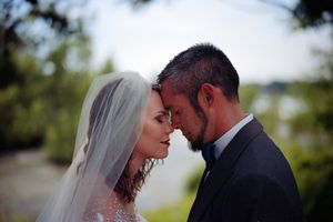 A romantic couple in wedding attire share an intimate moment outdoors in nature.