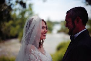 A bride and groom share a joyful moment together outdoors during their wedding ceremony.