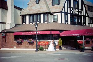 A Tudor-style building with a red awning houses a restaurant on a street corner in downtown.