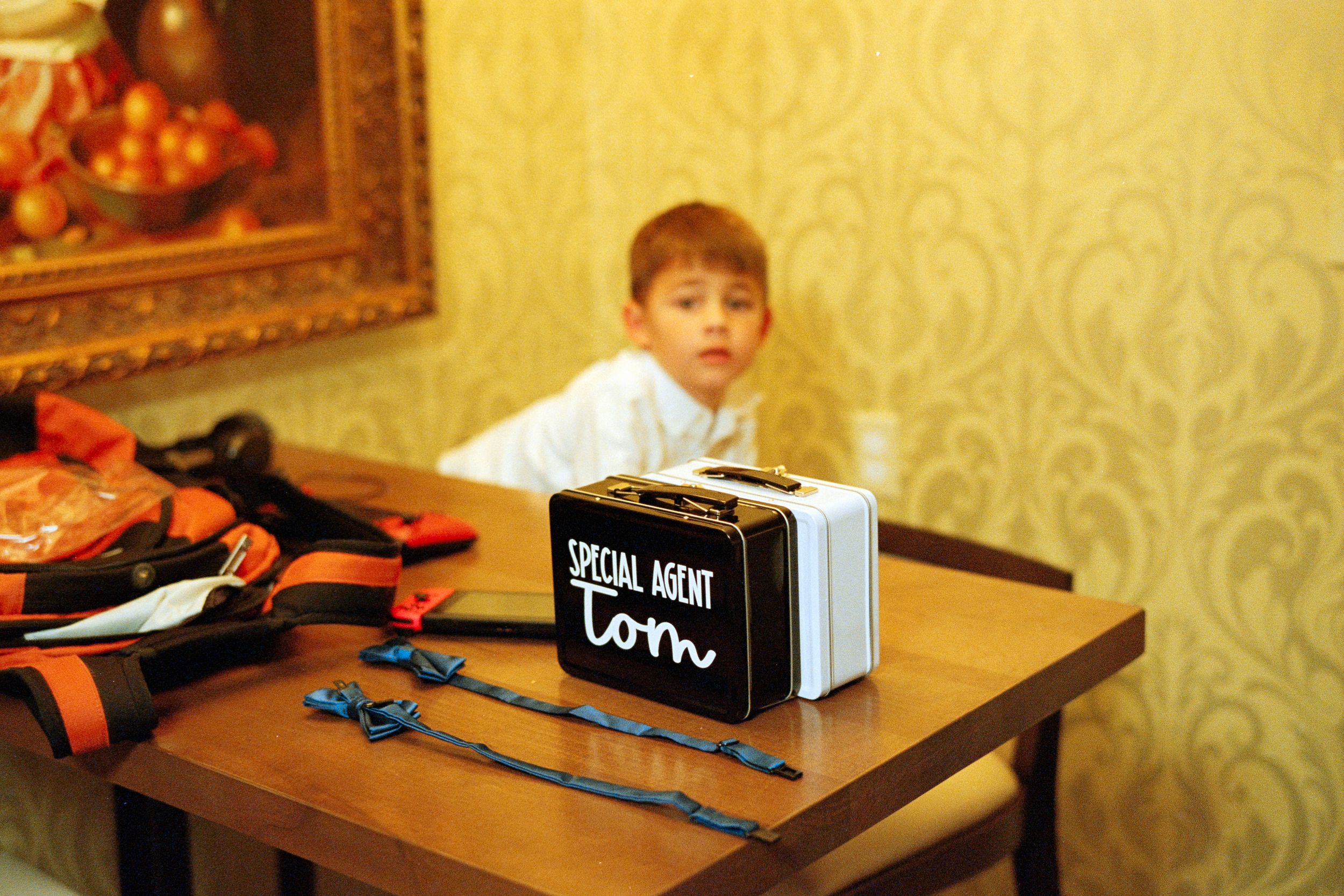 A small child sits behind a white and black sign that says 'bottom' on a wooden table.