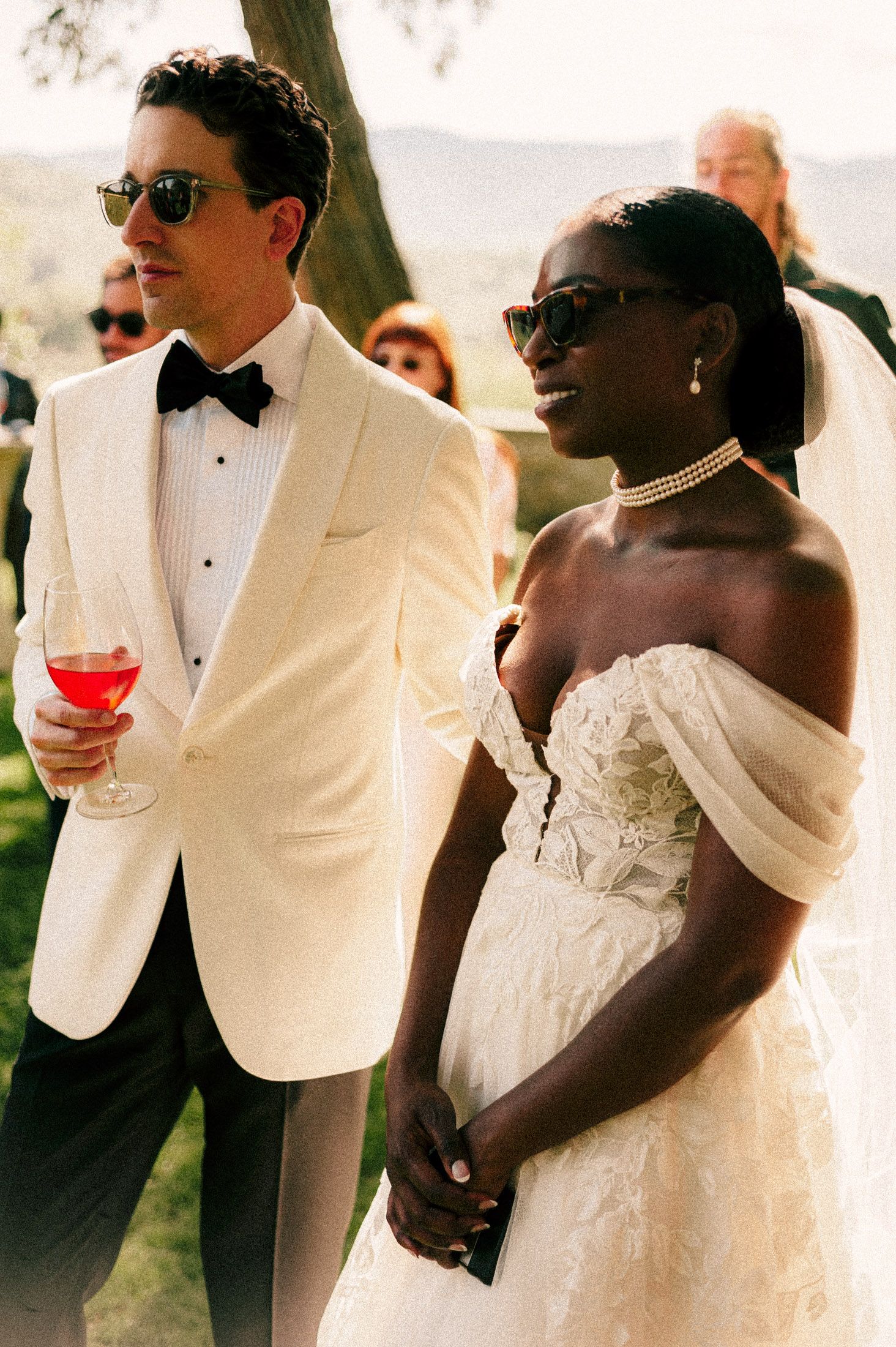 A romantic wedding celebration sequence showing a couple in white attire toasting and sharing intimate moments outdoors.