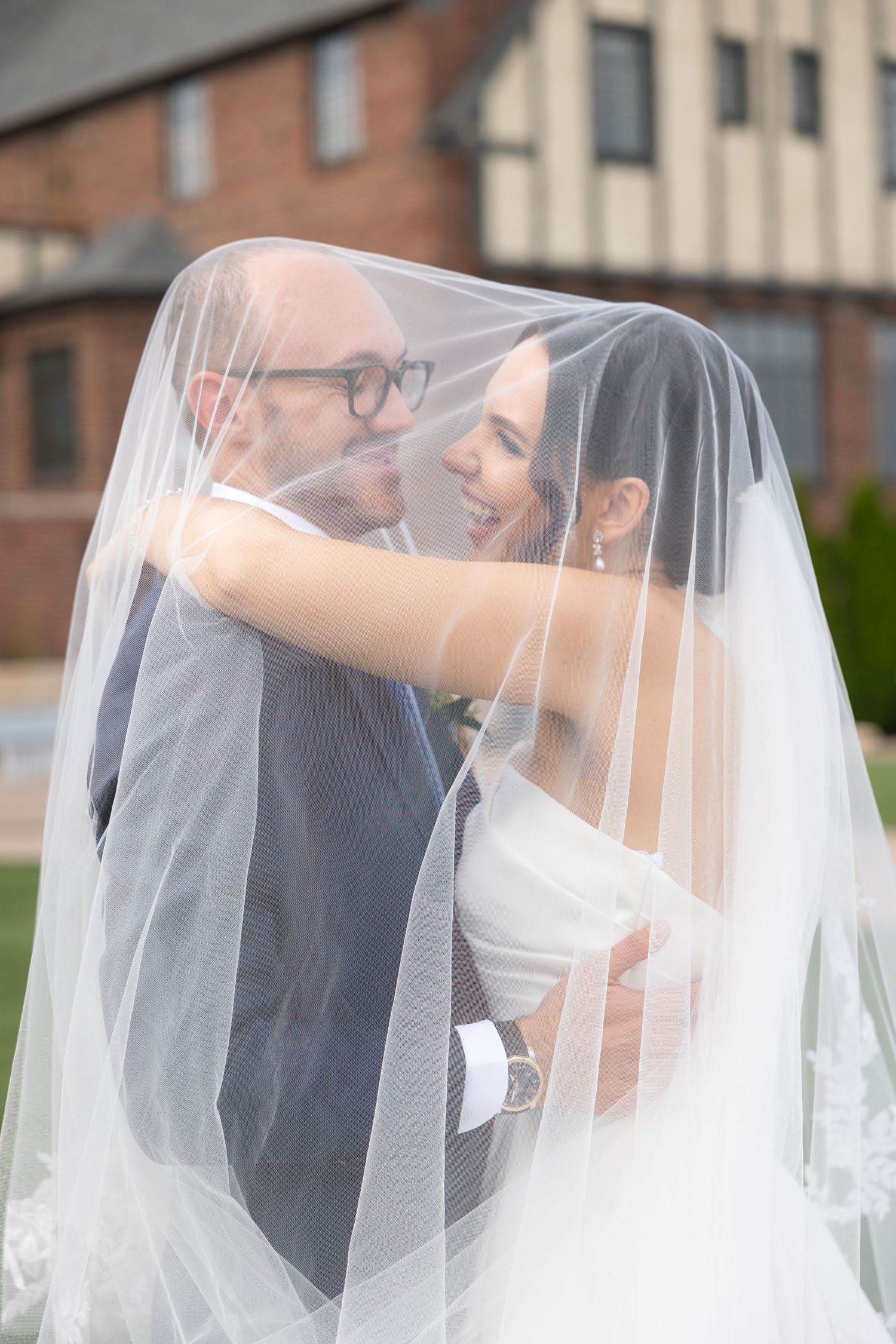 A romantic wedding moment captured through a flowing white veil as the couple shares a tender kiss. Rachel Martinez Photography, Novi MI