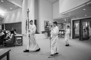 Black and white photo of altar servers in white robes preparing for a church service.