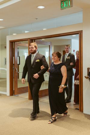 Wedding party members walking through modern hallway doors in formal attire.