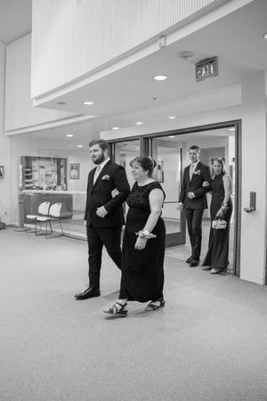 Men in black suits stand in a bright hallway during pre-wedding preparations.