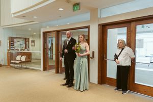 Wedding attendants in formal wear standing in a hallway before ceremony.
