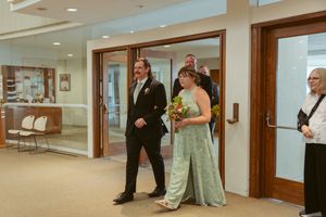 Wedding party members walking through glass doors in formal attire.