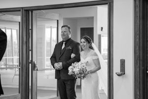 A black and white photo capturing a wedding entrance moment at a church doorway.