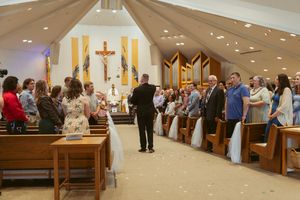 Wedding ceremony in progress inside a modern church with vaulted ceilings and gathered congregation.