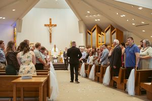 Church wedding ceremony with congregation standing in pews under vaulted ceiling.