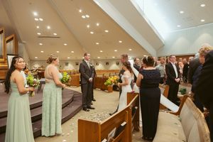 Wedding ceremony in progress with attendants in mint green dresses standing at altar.