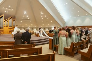 Panoramic shot of a church wedding ceremony showing the full sanctuary with guests seated in wooden pews.