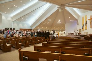 Interior of modern church with angular ceiling and wooden pews during wedding ceremony.