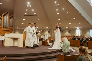 A traditional Catholic wedding ceremony takes place inside a modern church with an organ and white altar.