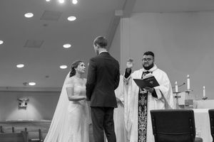 Wedding ceremony in progress inside a brightly lit church with candles and decorative elements.