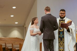Wedding ceremony in progress at church altar with priest officiating.