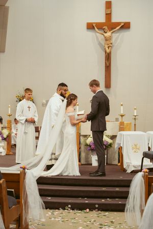 Priests and attendees gather at the altar during a Catholic wedding ceremony in a church.