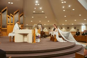 Wedding ceremony taking place in a modern church interior with organ pipes and recessed lighting.