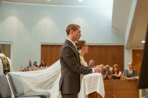 Church interior with long white fabric extending down the aisle during a wedding ceremony.