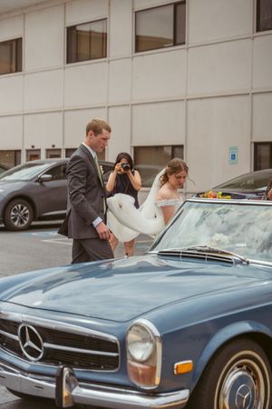 A classic blue Mercedes Benz convertible parked outside a modern building.