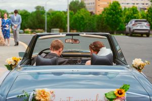 A couple departing in a classic blue convertible decorated with wedding flowers.