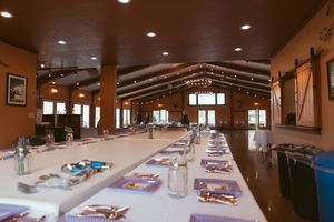 Long tables decorated with place settings and centerpieces fill an elegant banquet hall for a formal event.