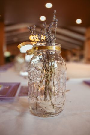 Mason jars filled with delicate sprigs of lavender and candles create an elegant rustic table centerpiece.