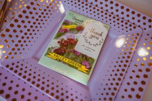 A 'thank you' greeting card sits on a pink perforated surface with glowing lights in the background.