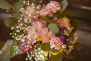 Delicate pink carnations and baby's breath floral arrangement with green eucalyptus leaves.