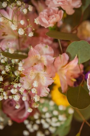 Pink roses and white baby's breath flowers create a romantic floral arrangement with green foliage.
