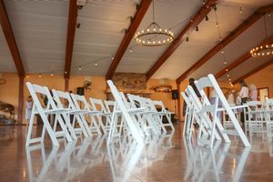 White folding chairs arranged in rows on polished concrete floor with wooden beam ceiling.