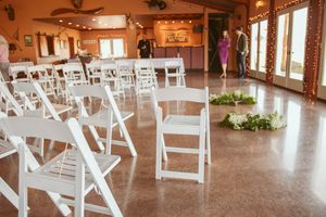 Wedding venue interior with white folding chairs arranged in rows and rustic wooden decor.