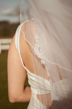 Close-up detail of delicate lace veil and white wedding dress back design.