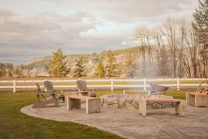 Outdoor patio seating area with white fence overlooking scenic mountain views at dusk.