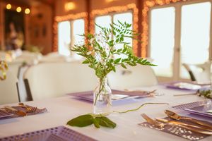 Elegant wedding reception table settings with glowing ambient lights and fresh greenery centerpieces at rustic venue.