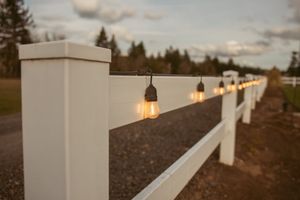 White stucco pillars with illuminated lights along a sloping commercial rooftop edge at dusk.