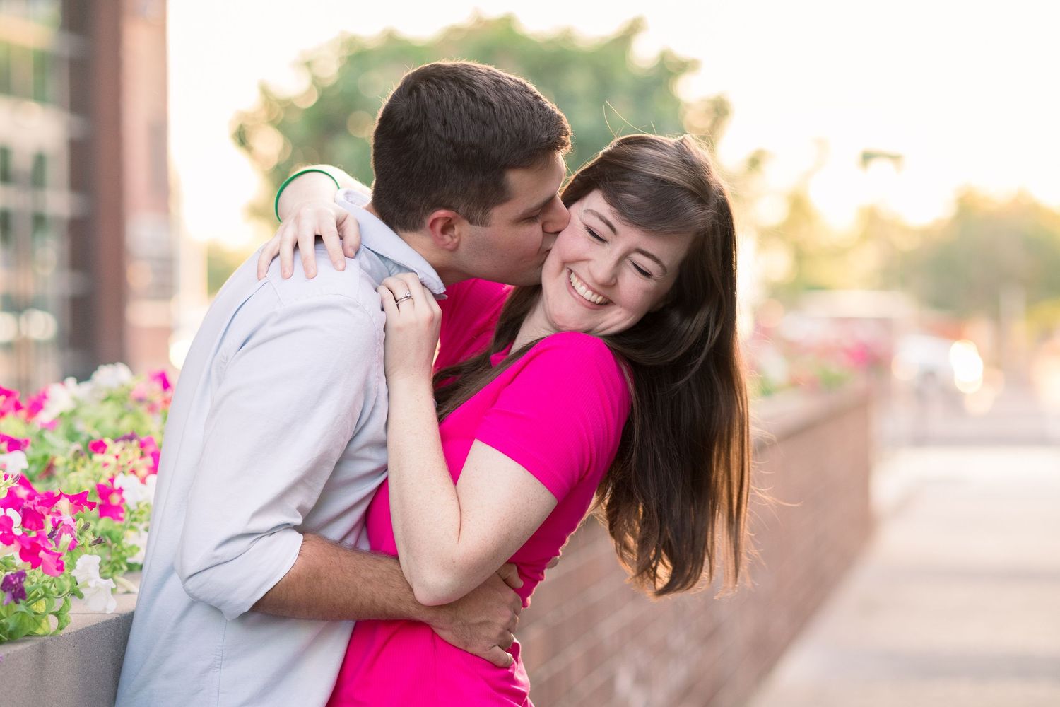 Light and airy photo in Downtown Gilbert taken by a Gilbert Family Photographer of a young couple in front of a bed of pink and white flower