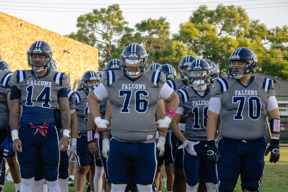 College football team members in navy uniforms walk together on game day.