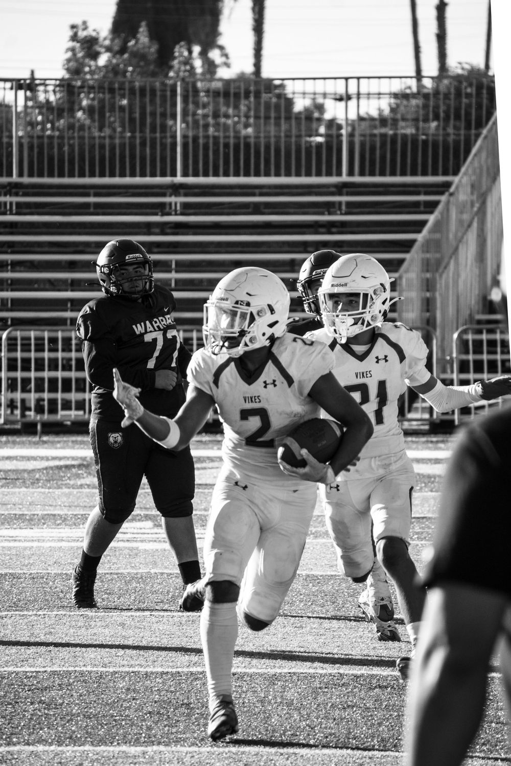 Black and white action shot of football players lined up at the line of scrimmage.